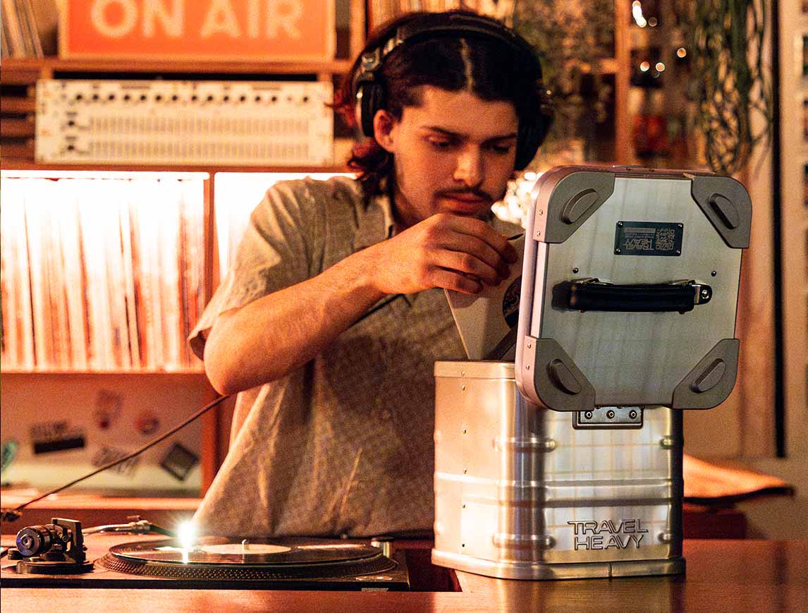 DJ in headphones picking a 7" single from a Travel Heavy 7" case next to the turntables